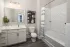 Bathroom with dark vanity cabinets, double sinks, and walk-in closet access at Abberly Royal Creek in Raleigh, NC.