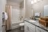 Elegant bathroom with modern granite countertops, stylish white cabinetry, and a relaxing bathtub setup.