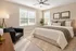 Elegant bedroom bathed in natural light, featuring a plush bed with cozy linens, a stylish armchair, and modern decor.