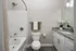 Modern bathroom with elegant granite countertop, sleek white cabinetry, and a pristine bathtub, enhanced by stylish decor and soft lighting.