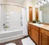 Bright, modern bathroom featuring a spacious bathtub, elegant wood cabinetry, and stylish lighting for a comfortable oasis.