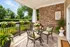 Charming outdoor patio with elegant wrought iron furniture, floral decor, and serene garden views.