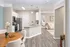 Inviting open-concept kitchen and living area featuring sleek stainless steel appliances, a modern granite countertop island, and elegant dining setup with a view into a cozy bedroom.