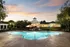 Elegant community pool area at sunset, featuring a well-lit clubhouse and beautifully landscaped surroundings.