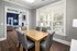 Bright dining room in modern apartment featuring elegant wood floors, stylish gray chairs, and large windows with a view of the pool area.
