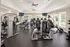Modern fitness center equipped with state-of-the-art exercise machines, weight racks, and flat-screen TVs, featuring ample natural light and a spacious workout environment.
