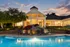 Elegant residential clubhouse at sunset with a shimmering pool, inviting lounge chairs, and beautifully landscaped gardens.