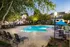 Charming apartment community with a serene outdoor pool area surrounded by lush greenery and cozy seating, perfect for relaxation.