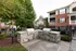 Charming outdoor grilling area with stone barbecue stations surrounded by lush greenery in a cozy apartment complex.