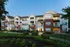 Charming multi-level apartment building with inviting balconies, nestled in lush landscaped grounds at dusk.