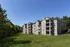 Charming apartment complex nestled in lush greenery, featuring spacious balconies and a beautifully manicured lawn.