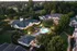 Charming aerial view of a serene apartment community with a sparkling pool, lush green landscaping, and cozy residential buildings at dusk.