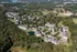 Aerial view of a picturesque suburban community surrounded by lush greenery, featuring modern apartment buildings and a serene pond, ideal for tranquil living.