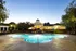 Luxurious apartment complex showcasing a sparkling pool and elegant clubhouse surrounded by lush greenery at dusk.