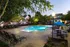 Charming apartment complex with a beautifully illuminated swimming pool, surrounded by lush greenery and inviting lounge chairs, perfect for relaxation.