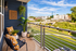 Charming balcony with modern decor, cozy seating, and lush greenery, offering a stunning view of the vibrant cityscape and serene park.