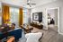 Chic living room with vibrant yellow curtains, modern decor, and an inviting view into a cozy bedroom.