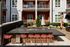 Chic outdoor patio area with modern bar seating, BBQ grill, and charming apartment balconies.
