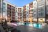 Modern apartment complex featuring a luxurious outdoor pool area with elegant lounge chairs, surrounded by stylish multi-story buildings.