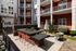 Inviting apartment courtyard with modern communal space, featuring a sleek outdoor kitchen, vibrant patio seating, and lush greenery for a perfect social gathering.