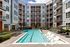 Modern apartment complex featuring a beautifully landscaped courtyard with a sparkling swimming pool and ample lounging areas.