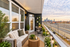 Charming city apartment balcony with cozy seating, lush greenery, and stunning skyline view.