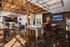 Stunning loft space with rustic wooden beams, polished dark floors, and a chic blend of leisure amenities including a pool table, arcade games, and modern lounge area.