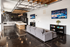 Chic modern lounge showcasing an open floor plan with a stylish kitchen, comfortable gray couches, sleek bar area, and wall-mounted TV for a perfect entertainment space.