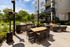 Luxurious apartment patio featuring a chic outdoor dining set, modern fire pit, and barbecue grill surrounded by lush greenery.