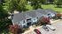 Charming two-story apartment complex with white balconies, surrounded by lush greenery and vibrant pink flowering trees, offering serene park views.