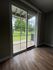 Bright room with elegant hardwood flooring and large sliding glass door opening to a serene green space.