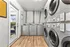 Modern laundry room with sleek washers and dryers, featuring a bright entryway and elegant wood flooring.