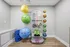 Modern fitness corner with colorful exercise balls, medicine balls, resistance bands, and yoga mats, perfect for a dynamic workout space.
