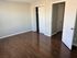 Bright and spacious bedroom with elegant wooden flooring and ample closet space.