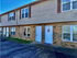 Charming two-story townhouse with brick facade and crisp white doors framed by large, inviting windows.