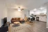 Inviting open-plan living space featuring a cozy brown sectional sofa, chic dining area, and modern white kitchen with stainless steel appliances.