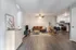 Modern open-plan living room with stylish furnishings, cozy brown sofa, ceiling fan, and sleek kitchen area in view.