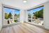 Bright and inviting room with expansive windows offering a stunning view of the leafy neighborhood, complemented by sleek wood flooring.
