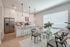 Bright and modern kitchen with sleek cabinetry, stainless steel appliances, and a chic dining area featuring a glass-top table, perfect for entertaining.