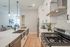 Modern kitchen with sleek stainless steel appliances, elegant white cabinetry, and a spacious marble island, seamlessly connecting to a cozy living area with stylish decor.