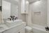 Elegant bathroom featuring chic marble tiles, modern black fixtures, and a sleek vanity with ample storage.