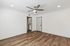 Modern apartment interior with sleek wood flooring, ceiling fan, and utility area with stacked washer and dryer.
