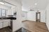 Elegant apartment kitchen with modern appliances, open to a bright living area with wood flooring and ceiling fan.