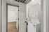 Modern apartment featuring an efficient in-unit laundry setup with a sleek stackable washer and dryer, accented by elegant wood flooring.