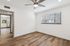 Bright and cozy room featuring elegant wood flooring, a sleek ceiling fan, and abundant natural light, leading to a modern kitchen.