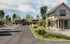 A picturesque driveway leading to a community club house surrounded by lush greenery and modern architecture.