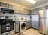 Modern kitchen with sleek gray cabinets, granite countertops, stainless steel appliances, and in-unit laundry.
