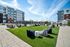 Modern apartment complex with a lush green courtyard and pool area, surrounded by comfortable outdoor seating.