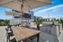 Chic outdoor patio with wooden tables, chairs, large umbrellas, and modern grills surrounded by lush greenery.