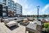 Elegant outdoor seating area with modern furnishings and a fire pit, overlooking a swimming pool at a luxury apartment complex.